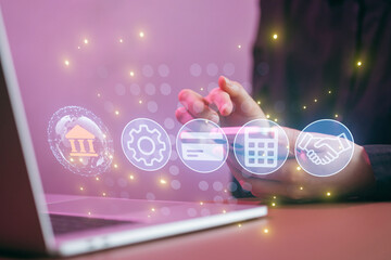 Hands using smartphone with financial icons and laptop on table