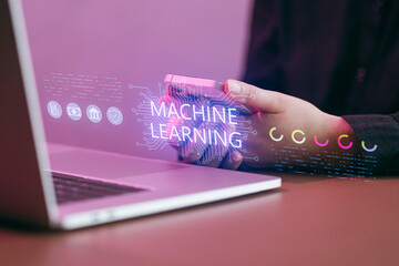 Person holding device while sitting in front of laptop with machine learning graphic displayed on screen