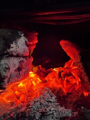 Close-up of glowing hot charcoal embers with intense red and orange fire light. Abstract fire texture background representing heat, energy, power, industry, danger, or combustion concept.