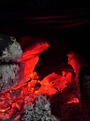 Close-up of glowing hot charcoal embers with intense red and orange fire light. Abstract fire texture background representing heat, energy, power, industry, danger, or combustion concept.
