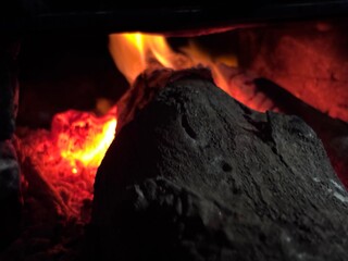 Close-up of glowing hot charcoal embers with intense red and orange fire light. Abstract fire texture background representing heat, energy, power, industry, danger, or combustion concept.