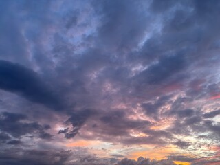 Dramatic cloudy sky during dusk with layered dark clouds and subtle pink sunset light. Atmospheric evening sky background for weather, nature, emotional mood, and abstract concepts.