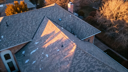 Roof with hail damage marked by inspection chalk concept. Aerial view of a residential roof at sunset, showcasing textures.