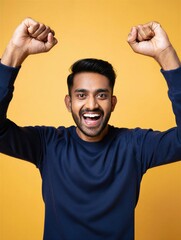 Fototapeta premium A joyful man with a big smile raises his fists in celebration against a bright yellow background. Happiness and achievement.