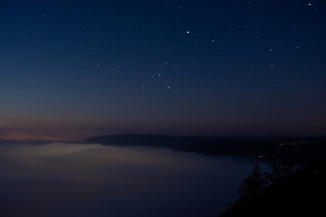 Naklejka premium Starry night over a foggy landscape