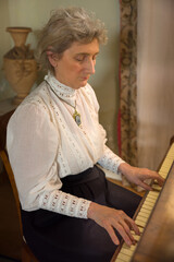Edwardian lady playing music on her piano