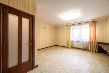 Obraz premium A light-colored room with beige tiled floor, striped wallpaper, wooden door with frosted glass panels, window with sheer curtains, ceiling light fixture, and a built-in bench