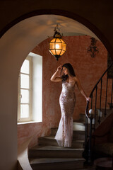 Woman in gold evening gown on spiral stairs