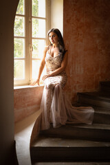 Woman in gold evening gown sitting in window