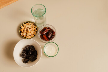 dates, nuts, and chestnuts alongside a glass of water and yogurt