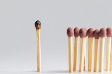 Burnout is depicted conceptually with single burnt matchstick standing apart from group of unlit matchsticks symbolizing mental exhaustion and isolation