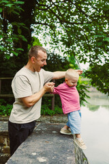 Father and child play near river while enjoying sunny day in park