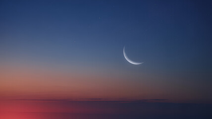 Crescent moon in a night sky with colorful sunset