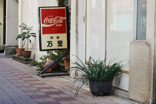 TOKYO, JAPAN - January 10, 2026: A sign featuring a Coca-Cola logo outside a Mahjong cafe in Tokyo's Chuo Ward. 