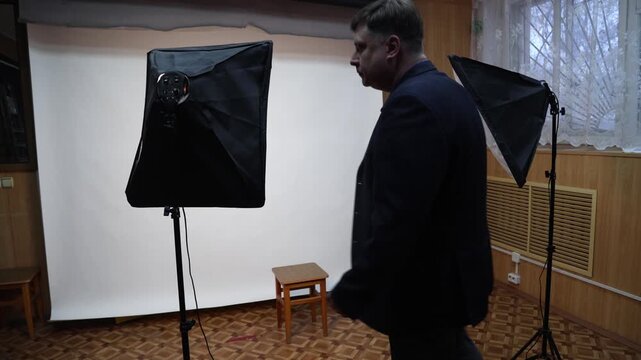 Photographer turning on softbox lighting equipment professional photo studio setup for portrait product photography.