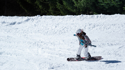 Girl (woman) on snowboard go down the hill by snow on the track of alps mountains in Italy during winter day light