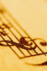 Abstract musical background featuring classical notation on aged paper, captured in soft warm light. Copy space.