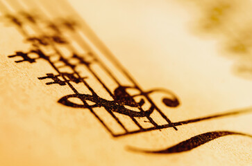 Macro close-up of musical notes on vintage sheet music with warm golden tones and shallow depth of field.