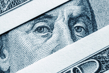 Macro close-up of US dollar banknote eyes, symbolizing money, power, financial control, and economic surveillance.