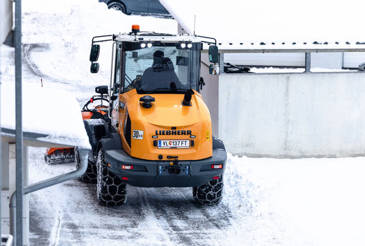 Villach, Austria - January 10, 2026: Liebherr snow plow vehicle clearing snow from a residential area, showcasing winter maintenance and urban infrastructure in action