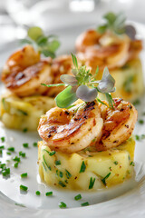 Gourmet American potato salad molded in round shape topped with honey mustard grilled shrimp and microgreens on white background
