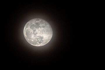 Full moon showing craters on hazy night. © Mark