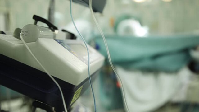 Timelapse shot of anesthesia equipment in a hospital operating room with surgical procedure blurred in background