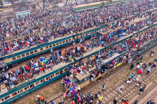 Tongi, Bangladesh - 12 January 2020: Aerial view of the Tongi Rail Station Road shows densely packed trains, a sea of faces on rooftops and platforms.