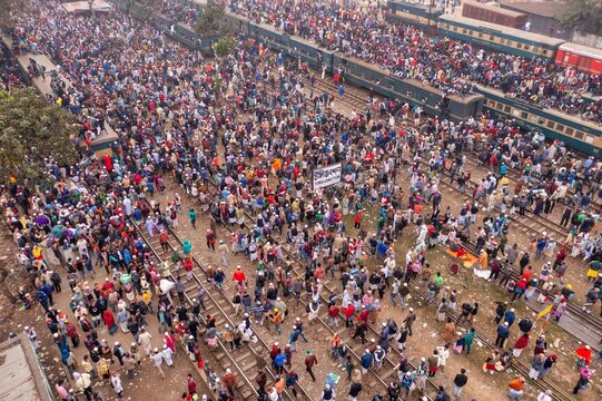 Tongi, Bangladesh - 12 January 2020: Aerial view of a dense crowd gathered near Tongi Rail Station, with trains visible and litter scattered around the tracks.