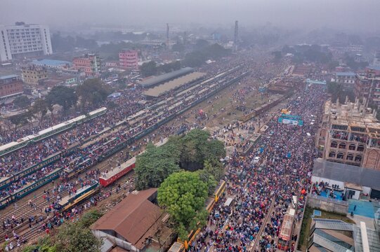 Tongi, Bangladesh - 12 January 2020: Aerial view of Tongi Rail Station Road bustling with crowds, trains, and surrounding buildings under a hazy sky.