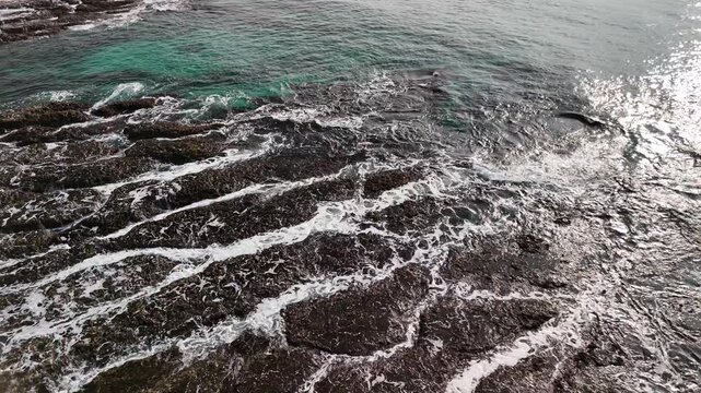B roll of eroded coastal rock with flowing seawater revealing grooves textures and patterns that symbolize memory time harmony and tension in a poetic natural shoreline scene