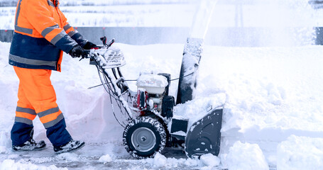 A janitor removes snow after a snowfall on the street with a snow blower