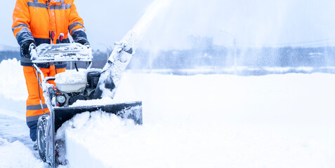 A janitor removes snow after a snowfall on the street with a snow blower