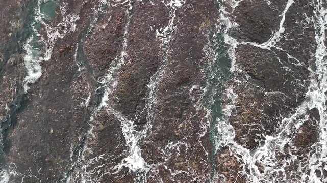 B roll of eroded coastal rock with flowing seawater revealing grooves textures and patterns that symbolize memory time harmony and tension in a poetic natural shoreline scene