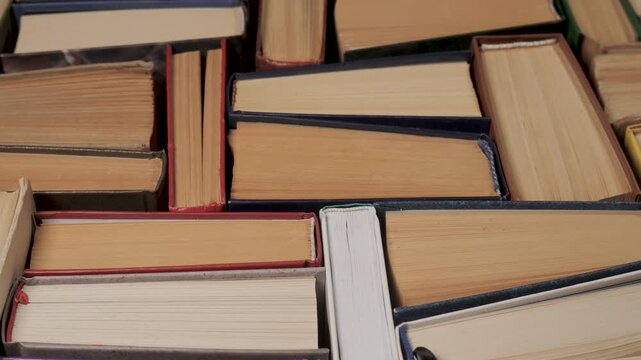 Stacked hardcover books with visible paper edges viewed from above, printed volumes arranged closely forming abstract educational background