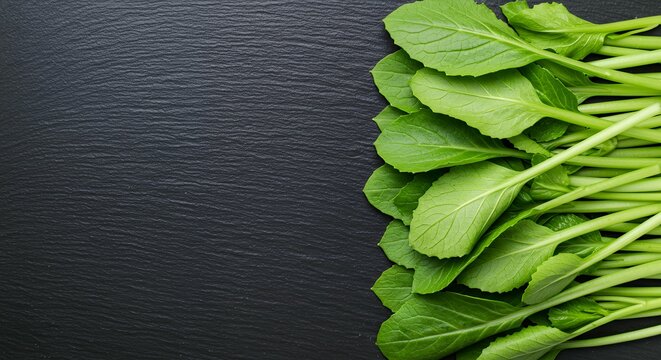 Organic Chinese Flowering Cabbage Choy Sum Arranged on Dark Stone Background, Overhead Shot of Fresh Asian Leafy Vegetables