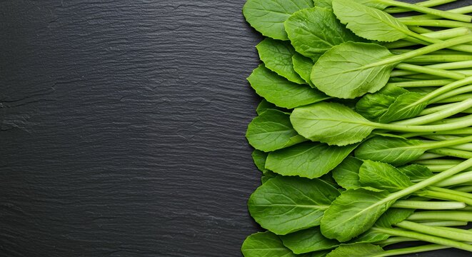 Close Up of Fresh Choy Sum Leafy Greens Lined Up on Black Slate Plate, High Quality Ingredient Concept for Healthy Living and Asian Food