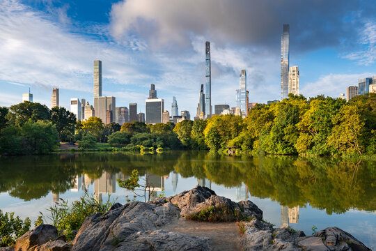 New York City Central Park lake reflecting Billionaires Row skyscrapers in morning light. Peaceful summer scene in Midtown Manhattan