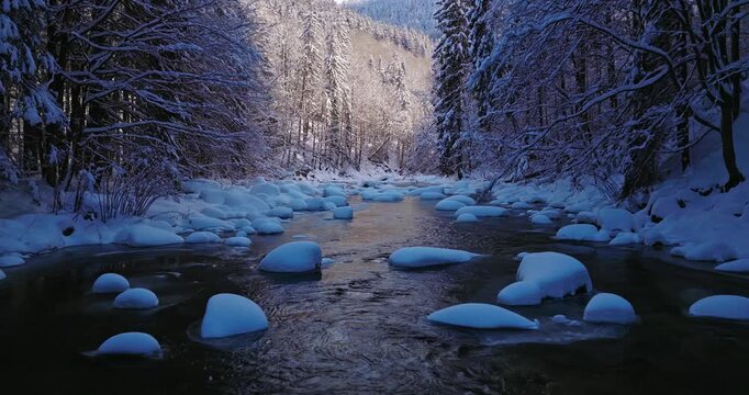 Peaceful flight over a snow-covered alpine stream. Flowing icy water, frozen rocks, and fresh snow create a calm winter atmosphere ideal for relaxation, meditation, and nature visuals.