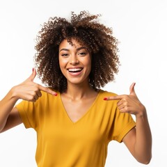 Happy young woman with curly hair pointing to herself, smiling widely, studio portrait against white background
