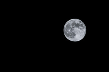 Bright full moon isolated on black night sky with copy space © AdobeTim82