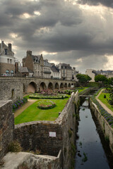 Historic medieval ramparts of Vannes overlooking landscaped gardens, with stone walls and traditional houses under a dramatic sky, showcasing Breton heritage, urban fortifications, and the harmony bet