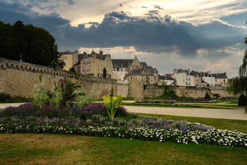 Historic medieval ramparts of Vannes overlooking landscaped gardens, with stone walls and traditional houses under a dramatic sky, showcasing Breton heritage, urban fortifications, and the harmony bet