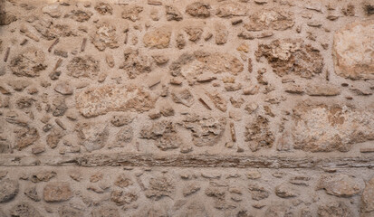 Weathered stone wall with rough texture and natural earthy tones in close-up.