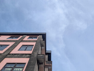 A view of a modern building with a cloudy blue sky in the background.