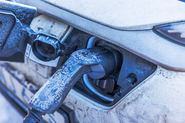 Close up view of frozen electric car charging plug connected to vehicle port during winter cold. Sweden.