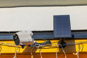 Close up view of outdoor security camera and solar panel covered with snow on villa wall. Sweden.