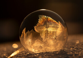 Zamrożona bańka mydlana, kryształy lodu w promieniach zachodzącego, zimowego słońca, tapeta. © mycatherina