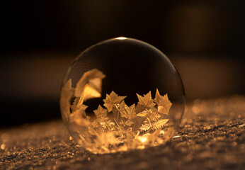 Zamrożona bańka mydlana, kryształy lodu w promieniach zachodzącego, zimowego słońca, tapeta. © mycatherina