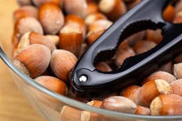 A black nutcracker and many hazelnuts. The nutcracker is arranged against a background of hazelnuts.